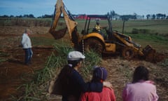 Doctor Rogelio Goiburú guides work at the dig while relatives of the disappeared and local residents look on.