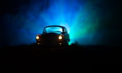 Silhouette of old vintage car in dark foggy toned background with glowing lights in low light, or silhouette of old crime car dark background. Selective focus