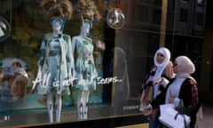 Two women walk past a Ted Baker window display on a high street