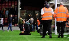 Orient fans sit on the pitch to try to hold up play up due to a medical emergency