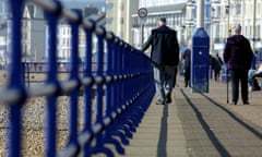 Older people walk along the beachfront promenade in Eastbourne