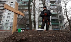 A local resident stands next to the grave of his friend killed in Mariupol