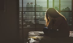 Woman sitting head in hands on the bed in the dark bedroom