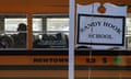 A Newtown school bus with a 'Sandy Hook School' sign in the foreground.