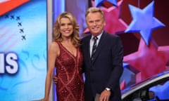 A white woman in a red sequined dress stands with a white man in a suit, their arms around each other, on a lighted red, white and blue stage.