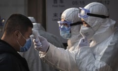 Chinese health workers check the temperature of people entering a subway station in Beijing in January 2020