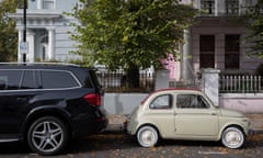 A large 4x4 SUV car parked behind a much smaller FIAT 500 among autumn leaves on Elgin Crescent in Notting Hill, on 7th October 2018, in London, England.<br>PW2AMK A large 4x4 SUV car parked behind a much smaller FIAT 500 among autumn leaves on Elgin Crescent in Notting Hill, on 7th October 2018, in London, England.