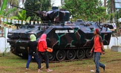 Residents walk past a tank outside a polling station in the town of Pantar, in Mindanao on 9 May as people vote in the Philippines’ presidential election.