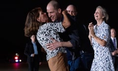 Evan Gershkovich grins as he hugs his mother, with a woman clasping her hands in joy behind him, and others standing in the background barely visible