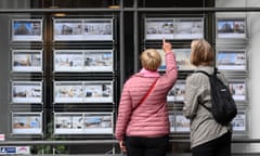 Two women point at listings on a UK estate agents’ window listings.