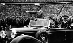 Adolf Hitler giving a nazi salute to a crowd of soldiers at a Nazi rally.