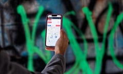 A smartphone is held up against a green graffiti background