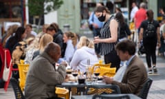 Waitress wearing a face covering serving diners at outside tables in Kensington, London.