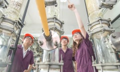 Engineering students in hard hats inspect a piece of industrial machinery