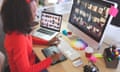 Female graphic designer using graphic tablet at desk<br>Side view of young mixed-race female graphic designer using graphic tablet at desk in a modern office