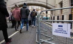 Crowds walking past temporary barriers under arch