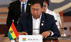 Luis Arce in front of a sign saying bolivia