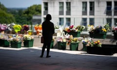 A person looks at flowers in green plastic containers