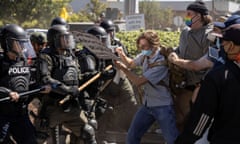 Police in riot gear use sticks to confront counter-protesters.