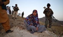 Salima Mazari sits on a hill observing the frontline against the Taliban surrounded by armed men.