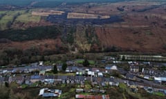 An aerial view of a landslide caused by a coal tip on a hillside above rows of terraced houses