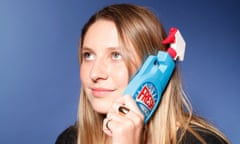 Victoria, wearing rings and bracelets, holds a phone case shaped like a detergent bottle with a spray attachment to her ear