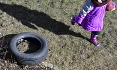 A girl carries a ball as she plays outside