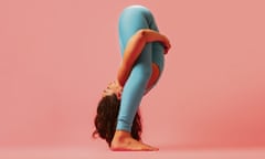A woman doing yoga with her head between her legs on a pink background