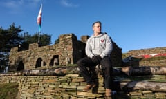 Mike Allen sitting on a stone wall by his small but impressive Welsh castle