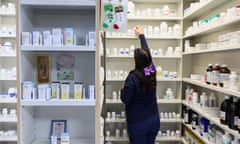 A pharmacy technician reaches for a bottle of medication