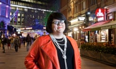 Amy Lamé standing on a street of bars and cafes in London at night