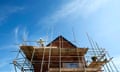 Builder standing on scaffolding around a house