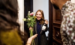 Woman holding bouquet and wine bottle while visiting friends<br>Young woman holding bouquet and wine bottle while visiting friends for dinner party