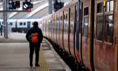 A train driver walks along a platform beside a train