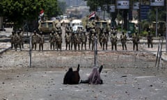 -- AFP PICTURES OF THE YEAR 2013 -- Two veiled Egyptian women, supporters of deposed president Mohamed Morsi, sit in front police standing behind barbed wire fencing that blocks the access to the headquarters of the Republican Guard in Cairo on July 8, 2013. Forty-two loyalists of Egypt’s ousted president were killed while demonstrating against last week’s military coup, triggering an Islamist uprising call and dashing the army’s hopes for an interim civilian administration. AFP PHOTO / MAHMUD HAMSMAHMUD HAMS/AFP/Getty Images