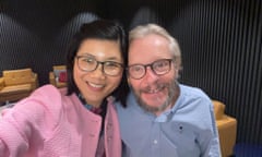 Ha Vu and Sean Turnell smile and pose for a photograph together. Ha Vu is wearing a light pink jacket and Turnell is wearing a blue shirt