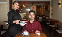 Ghofran Hamza pouring tea into the cup of George Dionysopoulos at their restaurant, Arabic Flavour, in Aberystwyth, Wales