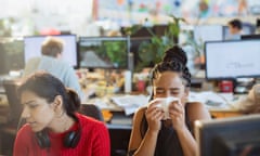 Woman with allergies sneezing into tissue in office