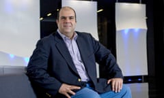 Stelios Haji-Ioannou sitting smiling on a chair for a formal photographic portrait