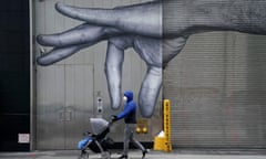 TOPSHOT-US-HEALTH-VIRUS-STREET ART<br>TOPSHOT - A person wears a facemask as they push a baby stroller past a loading dock mural of a hand on the Upper East Side of New York City on Presidents' Day, February 15, 2021. (Photo by TIMOTHY A. CLARY / AFP) (Photo by TIMOTHY A. CLARY/AFP via Getty Images)