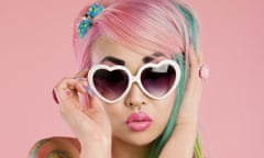Hyperfeminine young woman with pink hair posing wearing heart sunglasses