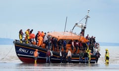 People climbing down to the beach from an RNLI vessel.