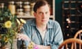 Luke Turner sitting at a kitchen table with a vase of flowers