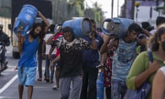 People carry gas cylinders bought at a distribution centre in Colombo