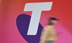 A women uses her mobile phones as she walks past a Telstra sign in Brisbane
