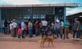 people stand in front of building as a dog walks by