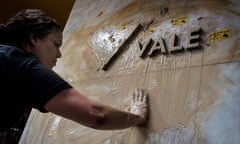 A woman spreads muddy water on the façade of Brazilian mining company Vale headquarters