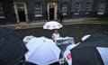 Journalist Laura Kuenssberg holds a white umbrella as members of the media gather in the rain outside No 10 Downing Street in London