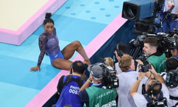 Simone Biles waits to see the final score for her floor routine as the press pack surrounds her.