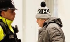 Boris Johnson, wearing a bobble hat with the letters GTFC, walking by a policeman.